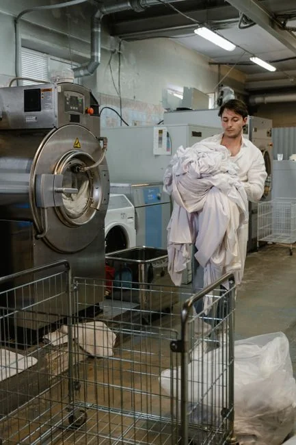 Une femme en pull gris essuie une table avec soin, illustrant le nettoyage à domicile dans un cadre confortable.